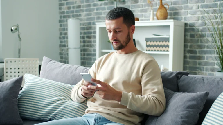 Man checking a smartphone while sitting on a sofa