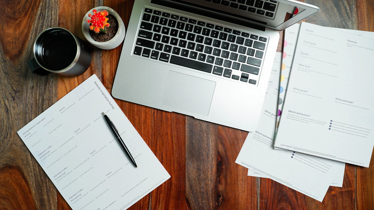 Laptop and printed planning pages on a wooden desk