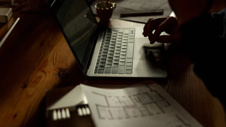 Person using a laptop beside paper documents